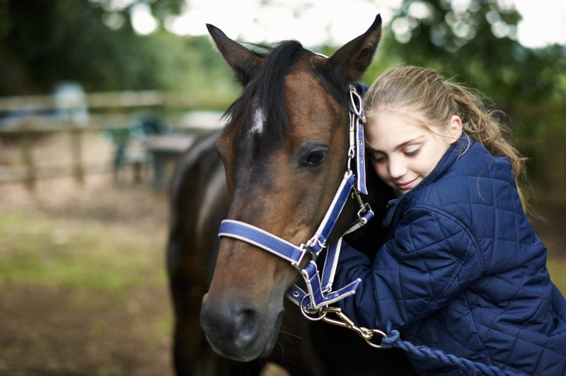 Girl horseback rider hugging horse